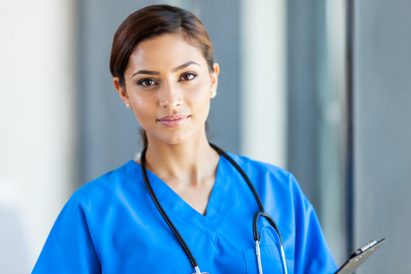 A Fleur de Rocaille nurse in blue scrubs with a stethoscope, holding a clipboard